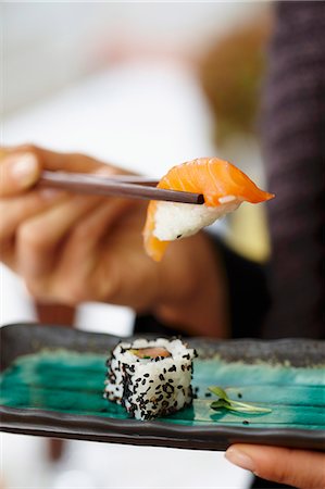 A person eating salmon sushi in a restaurant Stock Photo - Premium Royalty-Free, Code: 659-07738956
