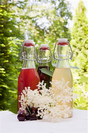 simsearch:659-07597339,k - Three glass bottles of homemade syrup on a garden table: rhubarb syrup, cherry syrup and elderflower syrup Stock Photo - Premium Royalty-Free, Code: 659-07958321