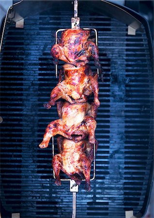 Barbecued chicken on a spit above a grill Stock Photo - Premium Royalty-Free, Code: 659-07959050