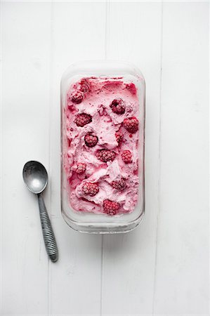 simsearch:659-07069181,k - A tub of frozen raspberry yogurt next to an ice cream scoop Stock Photo - Premium Royalty-Free, Code: 659-07959510