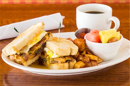 A breakfast sandwich with fried potatoes, fruit salad and coffee Stock Photo - Premium Royalty-Free, Code: 659-08147043
