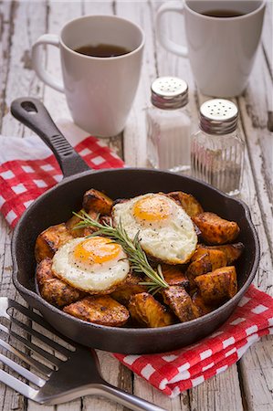 fish slice - Spiced baked potatoes with fried eggs and rosemary in a cast iron pan Stock Photo - Premium Royalty-Free, Code: 659-08148229