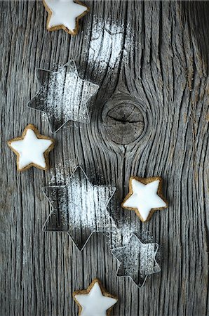 Star-shaped cutters with icing sugar and cinnamon stars on a wooden board Photographie de stock - Premium Libres de Droits, Code: 659-08148239