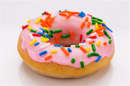 A doughnut with colourful sprinkles on a white surface Stock Photo - Premium Royalty-Free, Code: 659-08418899