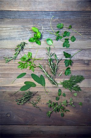 Various herbs (parsley, dill, oregano, thyme, sage, rosemary, lovage, coriander, basil) on a wooden surface Stock Photo - Premium Royalty-Free, Code: 659-08419697