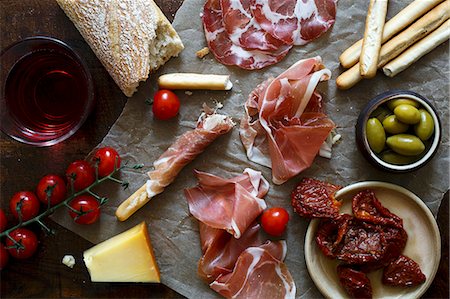 first course - Italian antepasto spread on wrinkled wax paper and dark wooden board Stock Photo - Premium Royalty-Free, Code: 659-08897122