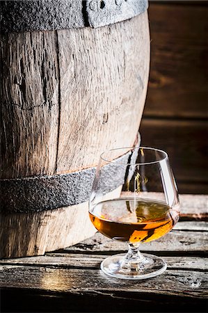 A glass of cognac next to an old wooden barrel Stock Photo - Premium Royalty-Free, Code: 659-08904760