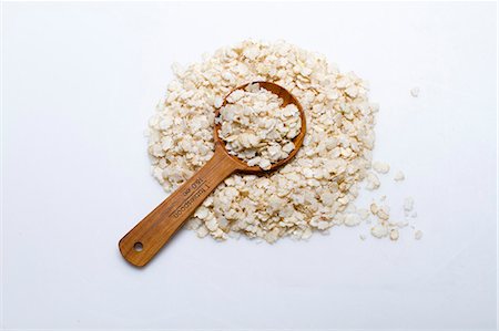 simsearch:659-07027144,k - A pile of rice flakes with a wooden spoon on a white surface Stock Photo - Premium Royalty-Free, Code: 659-08905246