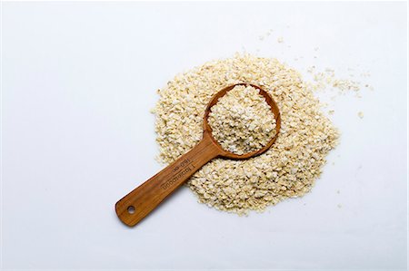 A pile of millet flakes with a wooden spoon on a white surface Stock Photo - Premium Royalty-Free, Code: 659-08905243