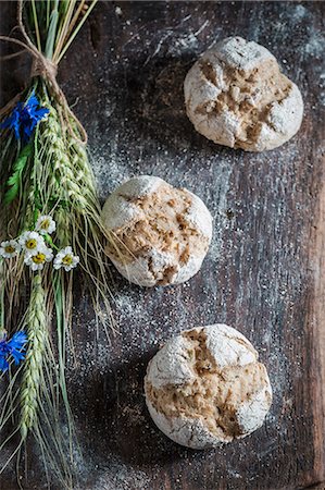 Healthy wholemeal buns with ears of oat and field flowers on a wooden board Stock Photo - Premium Royalty-Free, Code: 659-08906495