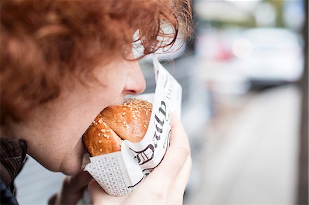 A red-haired teenager biting into a hamburger Stock Photo - Premium Royalty-Free, Code: 659-08902480