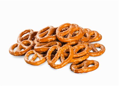 A pile of mini salted pretzels on a white surface Stock Photo - Premium Royalty-Free, Code: 659-08902727