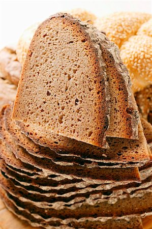 rye bread - Slices of farmhouse bread in a pile in front of assorted rolls Stock Photo - Premium Royalty-Free, Code: 659-01844151