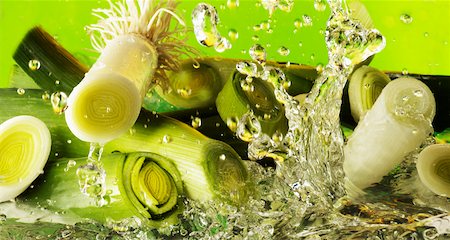 Pieces of leek falling into water against green background Stock Photo - Premium Royalty-Free, Code: 659-01849167