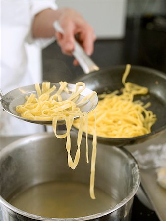 Putting tagliatelle into a frying pan Stock Photo - Premium Royalty-Free, Code: 659-01855994