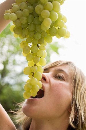 Woman holding fresh green grapes above her mouth Stock Photo - Premium Royalty-Free, Code: 659-01858267
