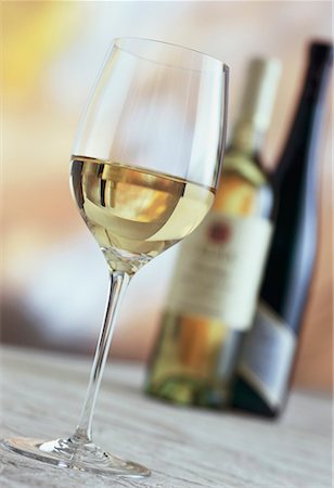 simsearch:659-06186663,k - A glass of white wine, white wine bottles behind Stock Photo - Premium Royalty-Free, Code: 659-01850054