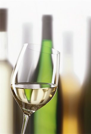 simsearch:659-06186663,k - Glass of white wine in front of white wine bottles Stock Photo - Premium Royalty-Free, Code: 659-01850058