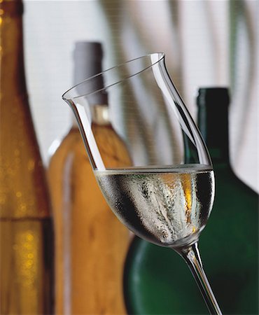 simsearch:659-06186663,k - Glass of white wine, various white wine bottles behind Stock Photo - Premium Royalty-Free, Code: 659-01850053