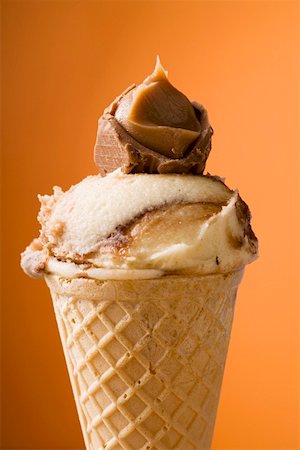 Caramel ice cream in wafer cone against orange background Stock Photo - Premium Royalty-Free, Code: 659-01850222