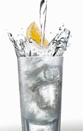 Pouring water into a glass with a wedge of lemon Stock Photo - Premium Royalty-Free, Code: 659-01851448