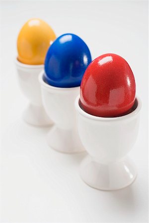simsearch:659-03536847,k - Three coloured eggs in egg cups Foto de stock - Sin royalties Premium, Código: 659-01864281