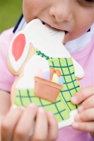 easter cookie - Child biting into Easter Bunny biscuit Stock Photo - Premium Royalty-Free, Code: 659-01867415
