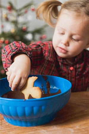 Girl dipping Christmas biscuit into chocolate icing Foto de stock - Sin royalties Premium, Código: 659-01861860