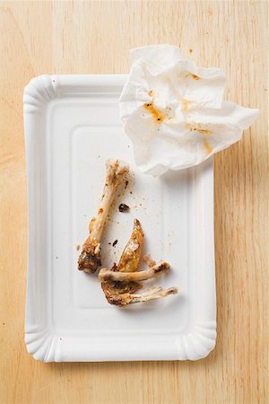 Chicken bones and paper napkin on paper plate Stock Photo - Premium Royalty-Free, Code: 659-01862258