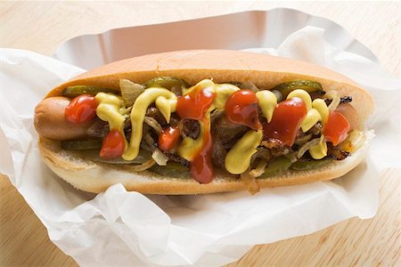 Hot dog with mustard, ketchup, gherkins and onions Stock Photo - Premium Royalty-Free, Code: 659-01862604