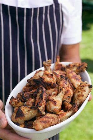 Man in apron holding grilled chicken wings Stock Photo - Premium Royalty-Free, Code: 659-02211963