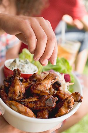 Hand reaching for grilled chicken wings Stock Photo - Premium Royalty-Free, Code: 659-02211997