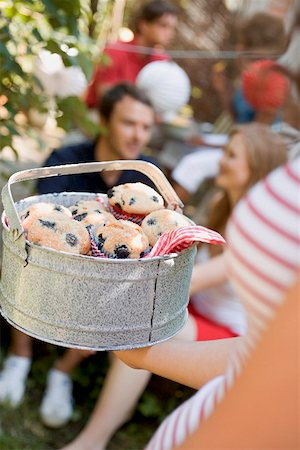 Woman holding a tin of blueberry muffins at a garden party Stock Photo - Premium Royalty-Free, Code: 659-02212118