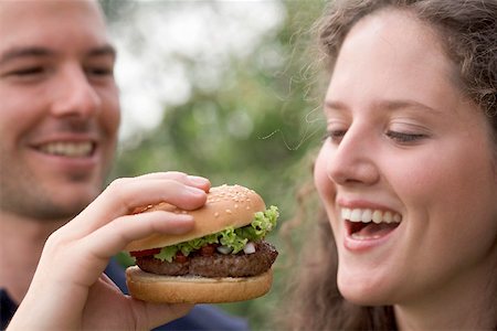 Man offering woman a bite of hamburger Stock Photo - Premium Royalty-Free, Code: 659-02212696