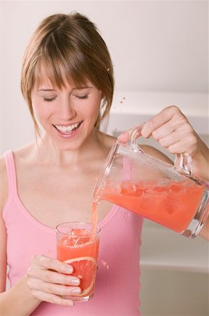 simsearch:659-06495307,k - Woman pouring pink grapefruit juice into glass Stock Photo - Premium Royalty-Free, Code: 659-02213037