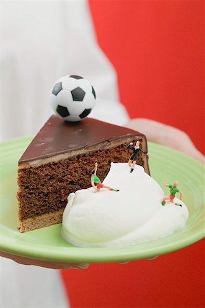 simsearch:659-02213122,k - Person holding piece of Sacher torte with cream & football Stock Photo - Premium Royalty-Free, Code: 659-02213097