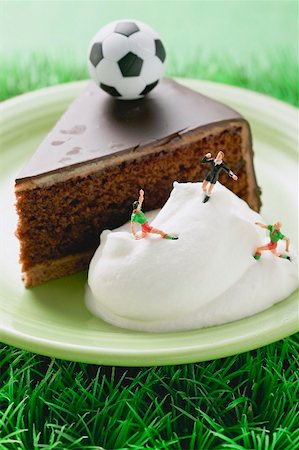Piece of Sacher torte with cream and toy football Stock Photo - Premium Royalty-Free, Code: 659-02213098