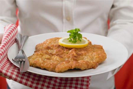 Woman holding plate of Wiener schnitzel (veal escalope) Stock Photo - Premium Royalty-Free, Code: 659-02213124