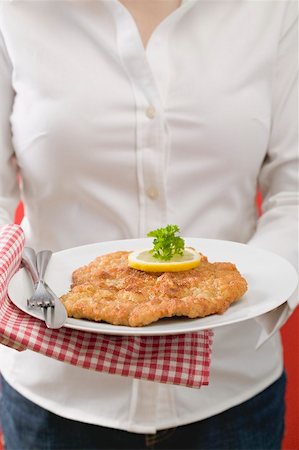 Woman holding plate of Wiener Schnitzel (veal escalope) Stock Photo - Premium Royalty-Free, Code: 659-02213123