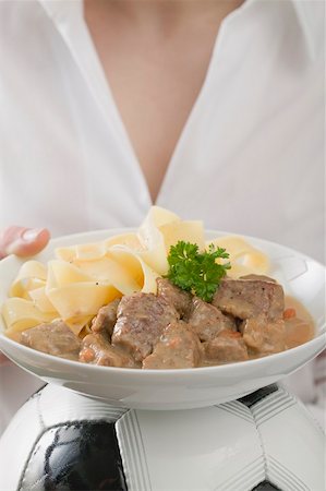 simsearch:659-02213122,k - Woman holding plate of Zürcher Geschnetzeltes (veal dish) on football Stock Photo - Premium Royalty-Free, Code: 659-02213137