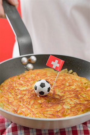 simsearch:659-02213122,k - Hand holding frying pan with rösti, toy football & Swiss flag Stock Photo - Premium Royalty-Free, Code: 659-02213133