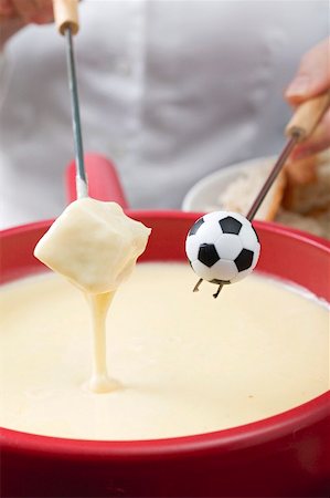 simsearch:659-02213122,k - Woman eating cheese fondue, toy football on fondue fork Stock Photo - Premium Royalty-Free, Code: 659-02213150