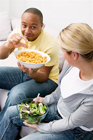Couple on sofa with peanut puffs and salad Stock Photo - Premium Royalty-Free, Code: 659-02213861