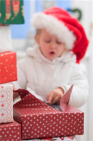 simsearch:659-03526649,k - Child in Father Christmas hat opening Christmas parcel Stock Photo - Premium Royalty-Free, Code: 659-03524967