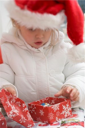 simsearch:659-03526649,k - Small girl in Father Christmas hat opening Christmas parcel Stock Photo - Premium Royalty-Free, Code: 659-03524971