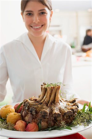 Young woman serving rack of pork for Christmas Stock Photo - Premium Royalty-Free, Code: 659-03525119