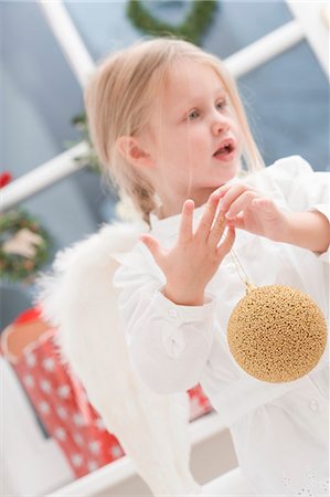 Small girl with angel's wings holding Christmas bauble Foto de stock - Sin royalties Premium, Código: 659-03525473