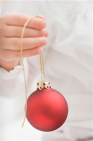 Child holding Christmas bauble with gold string Stock Photo - Premium Royalty-Free, Code: 659-03525504