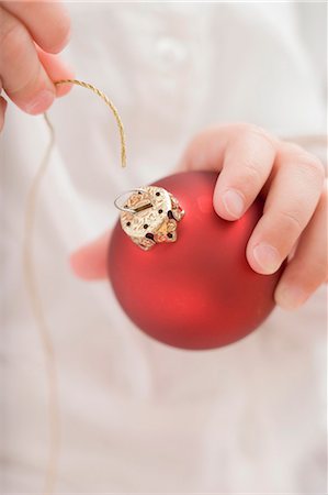 Child threading string through top of Christmas bauble Stock Photo - Premium Royalty-Free, Code: 659-03525503