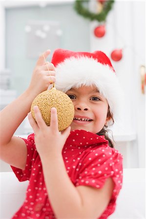 Small girl in Father Christmas hat holding Christmas bauble Foto de stock - Sin royalties Premium, Código: 659-03525787